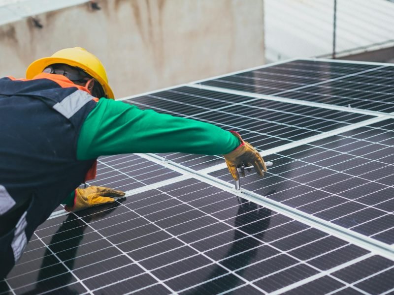 Technician installing solar panels on a rooftop for sustainable energy solutions.